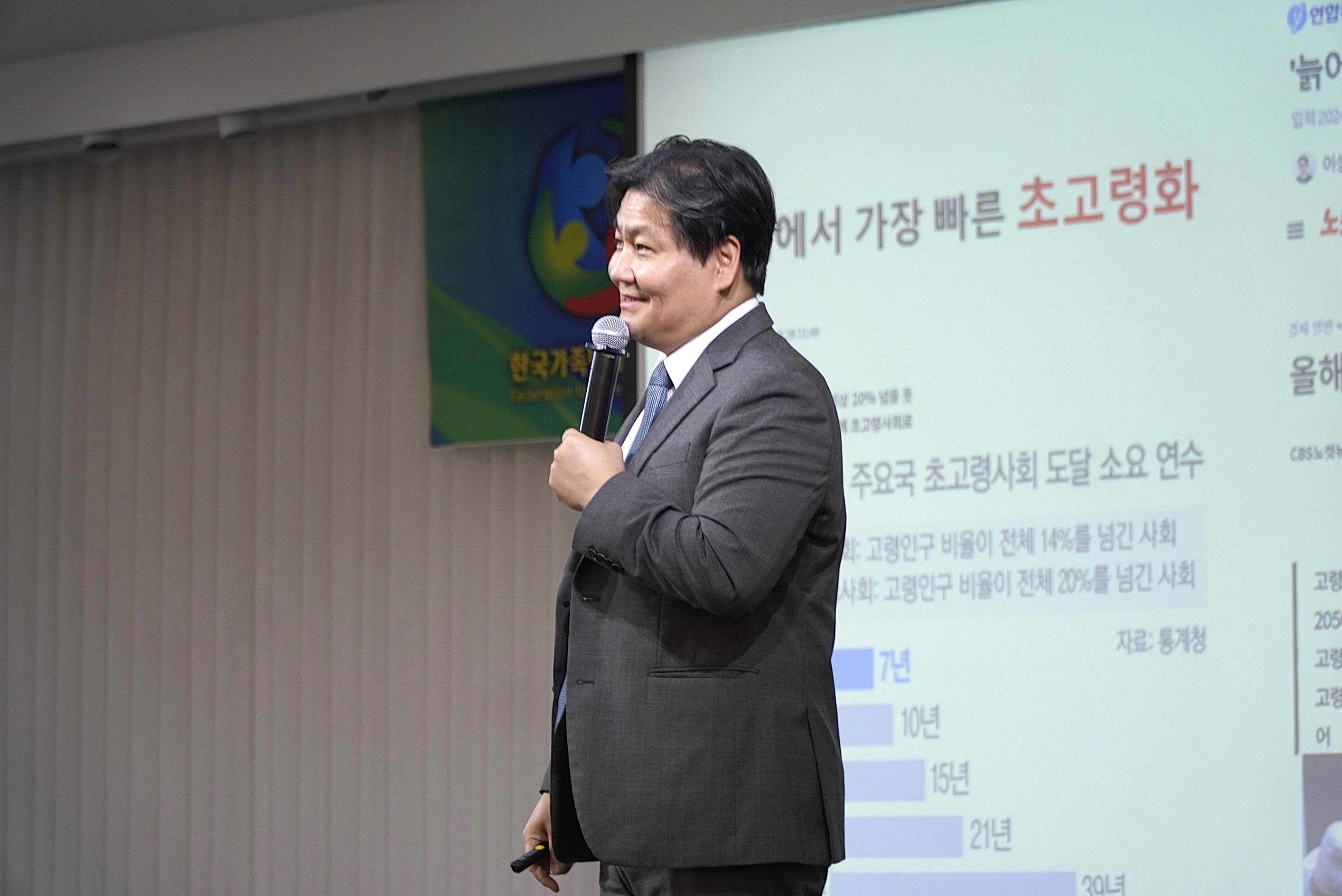 시민강연 현장에서 발표 화면 앞 강연자가 마이크를 들고 강연하는 모습