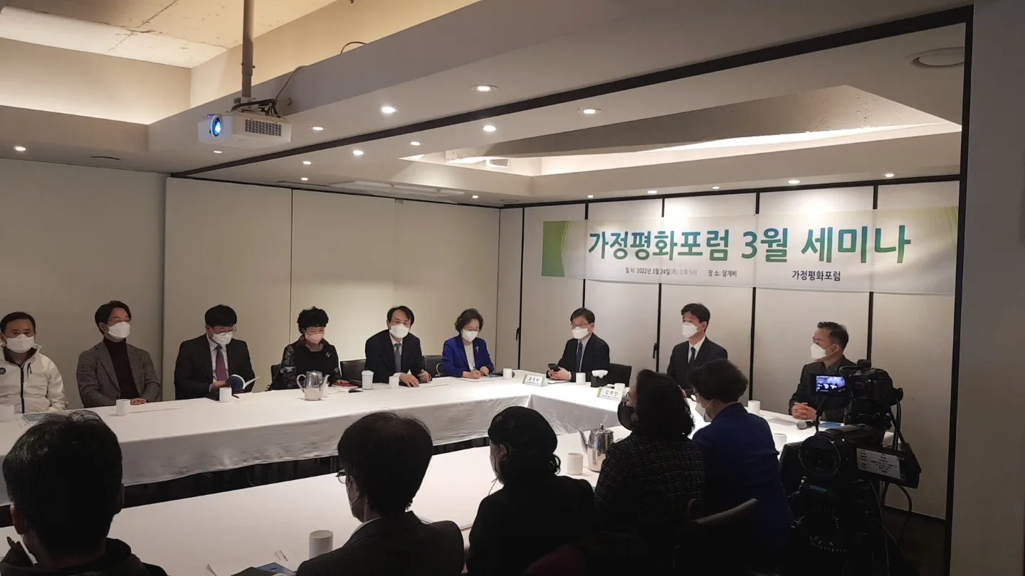 2022년 3월 24일 가정평화포럼 3월 세미나 현수막 아래 ㄷ자 탁자에 둘러앉아 토론하는 참석자들