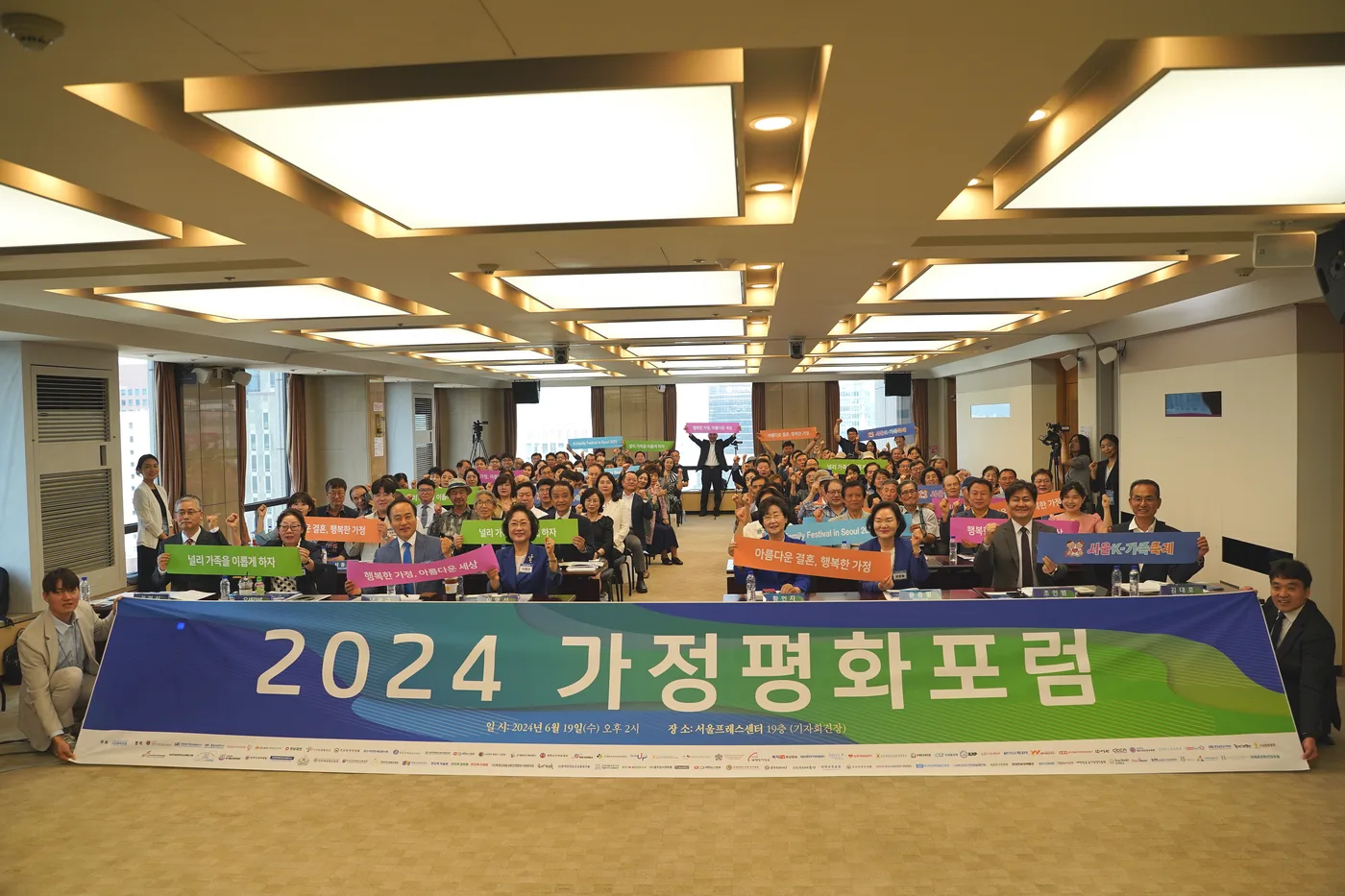 2024 가정평화포럼 현수막 앞에서 가족 관련 문구를 든 참석자들